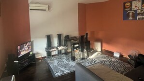 Un salon avec un téléviseur à écran plat, deux fauteuils noirs, un tapis à motifs zébrés et une table basse.