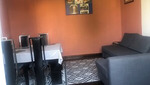 Un salon avec un canapé, une table à manger et des chaises, et un mur orné de posters encadrés.