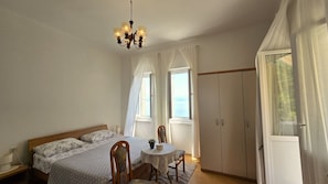 Una camera da letto con un letto, un tavolo, sedie, un armadio e un lampadario.
