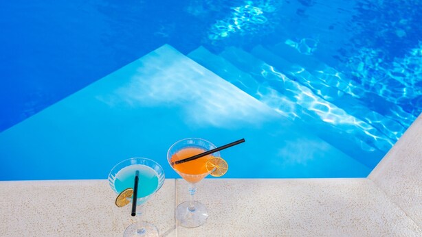 Deux cocktails sur une table au bord de la piscine, avec une vue dégagée sur le bassin.