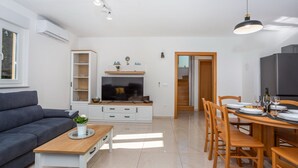 Un salon moderne comprenant un canapé, un téléviseur et un coin repas avec des chaises et une table.