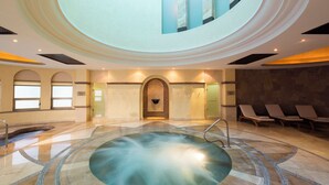Ett spaområde med ett bubbelbad, solstolar och en stenmur.