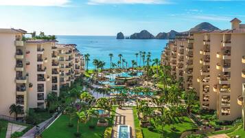 Un resort con varias edificaciones, un área de piscina central y vista al océano.