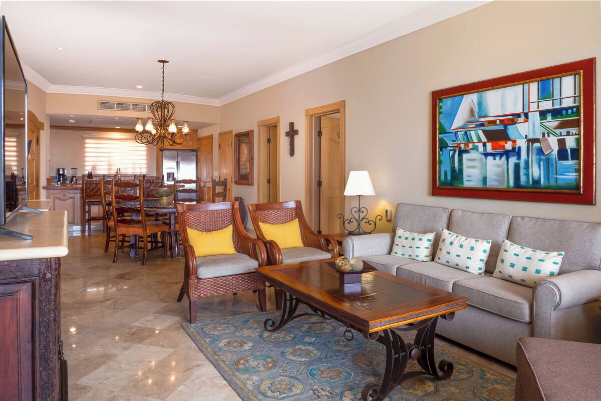 A spacious living room with a sofa, chairs, a coffee table, and a dining area with chairs and a table.