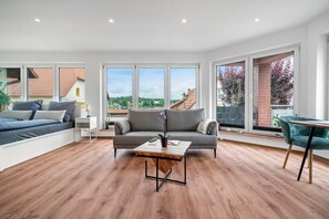 Ein modernes Wohnzimmer mit einer Couch, einem Couchtisch und Blick ins Freie.