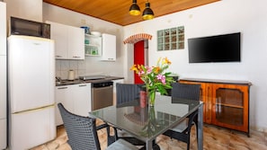 A compact kitchen with a microwave, refrigerator, sink, and a dining area with a table and chairs.