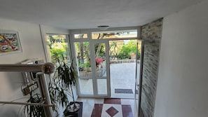 A hallway leading to a glass door with a view of a garden.