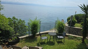 A terrace with a view of a lake, outdoor seating, and a chain-link fence. - Apartman Villa Adelle - Lovran by Villas Guide (Lovran)