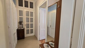 A hallway with a white door, a small table with a vase, and a wooden cabinet.