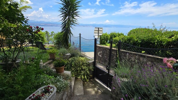 A garden with a view of the sea, a stone wall, and a metal gate. - Apartman Villa Adelle - Lovran by Villas Guide (Lovran)