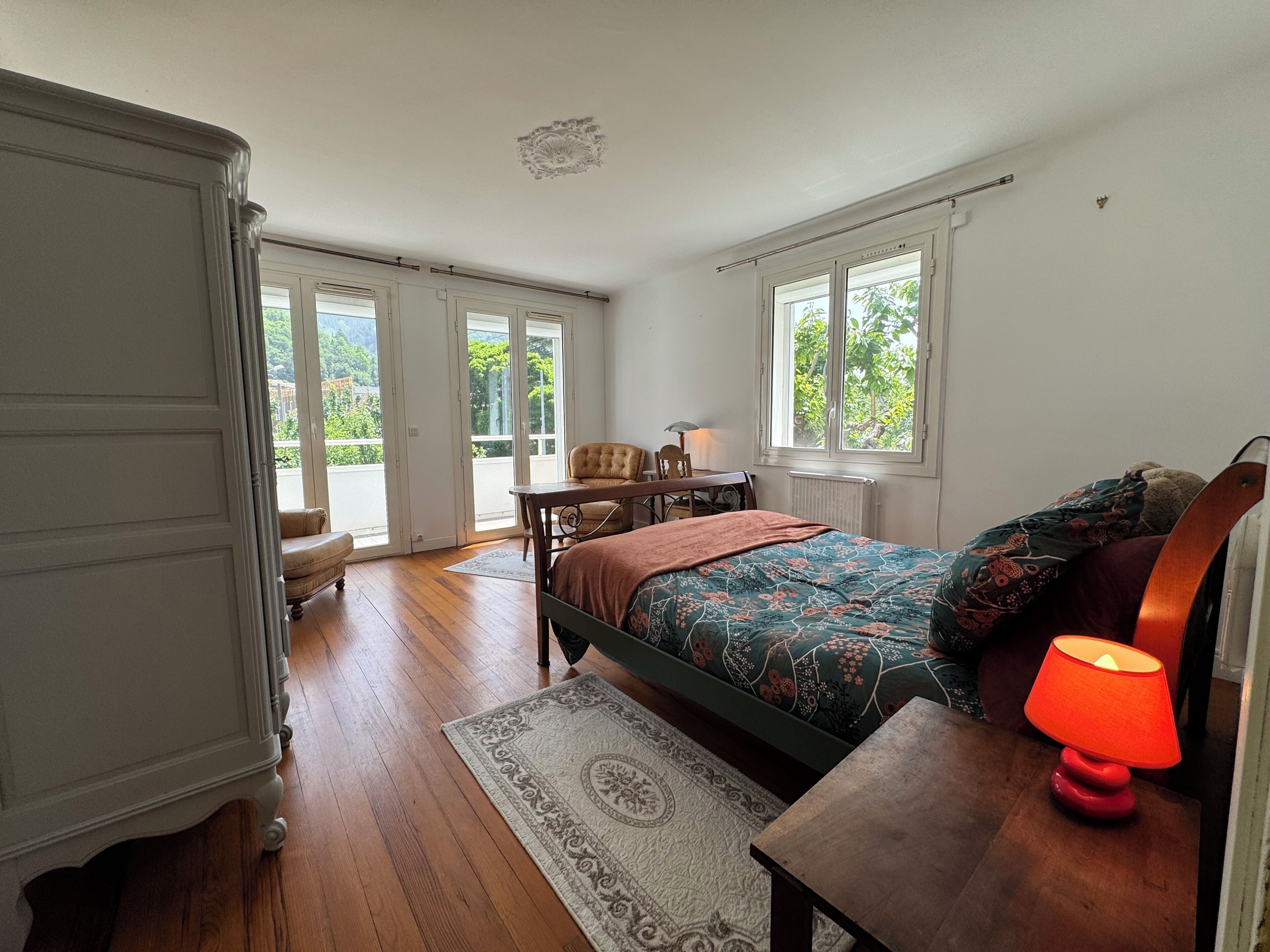 Ein Schlafzimmer mit Bett, Nachttisch, Stuhl, Schreibtisch und Fenster.