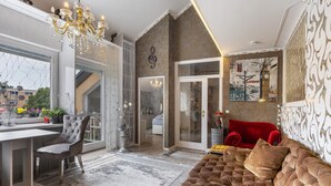 A spacious living area with a large window, a chandelier, a red sofa, and a wall-mounted artwork. - Quiet Berlin-Steglitz Apartment with Shared Garden, Balcony & Wi-Fi (Berlin)