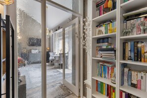 A room with a bookshelf, a door leading to another room, and a patterned rug.