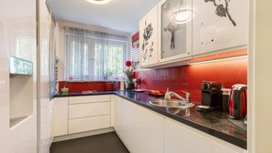 A kitchen with white cabinets, a black countertop, a sink, and a coffee maker. - Quiet Berlin-Steglitz Apartment with Shared Garden, Balcony & Wi-Fi (Berlin)