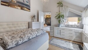 A bedroom with a bed, a dresser, a mirror, a chandelier, and a window with curtains. - Quiet Berlin-Steglitz Apartment with Shared Garden, Balcony & Wi-Fi (Berlin)