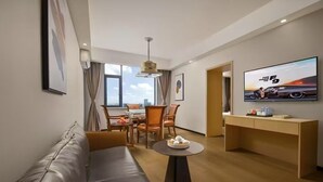A modern hotel room with a leather sofa, a dining table with chairs, a flat-screen TV, and a large window offering a city view. - Chengdu Ximao Hotel (Chengdu)