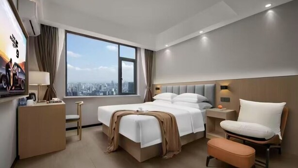 A modern hotel room with a large bed, a desk, a chair, and a view of the city. - Chengdu Ximao Hotel (Chengdu)