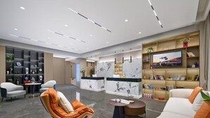 A modern hotel lobby with a reception desk, seating area, and a bookshelf. - Chengdu Ximao Hotel (Chengdu)