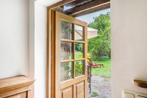 Une porte en bois avec des panneaux de verre, un mur en pierre et une vue sur le jardin.