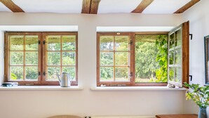 Una habitació amb dues finestres, un radiador, una taula de fusta i una cadira.