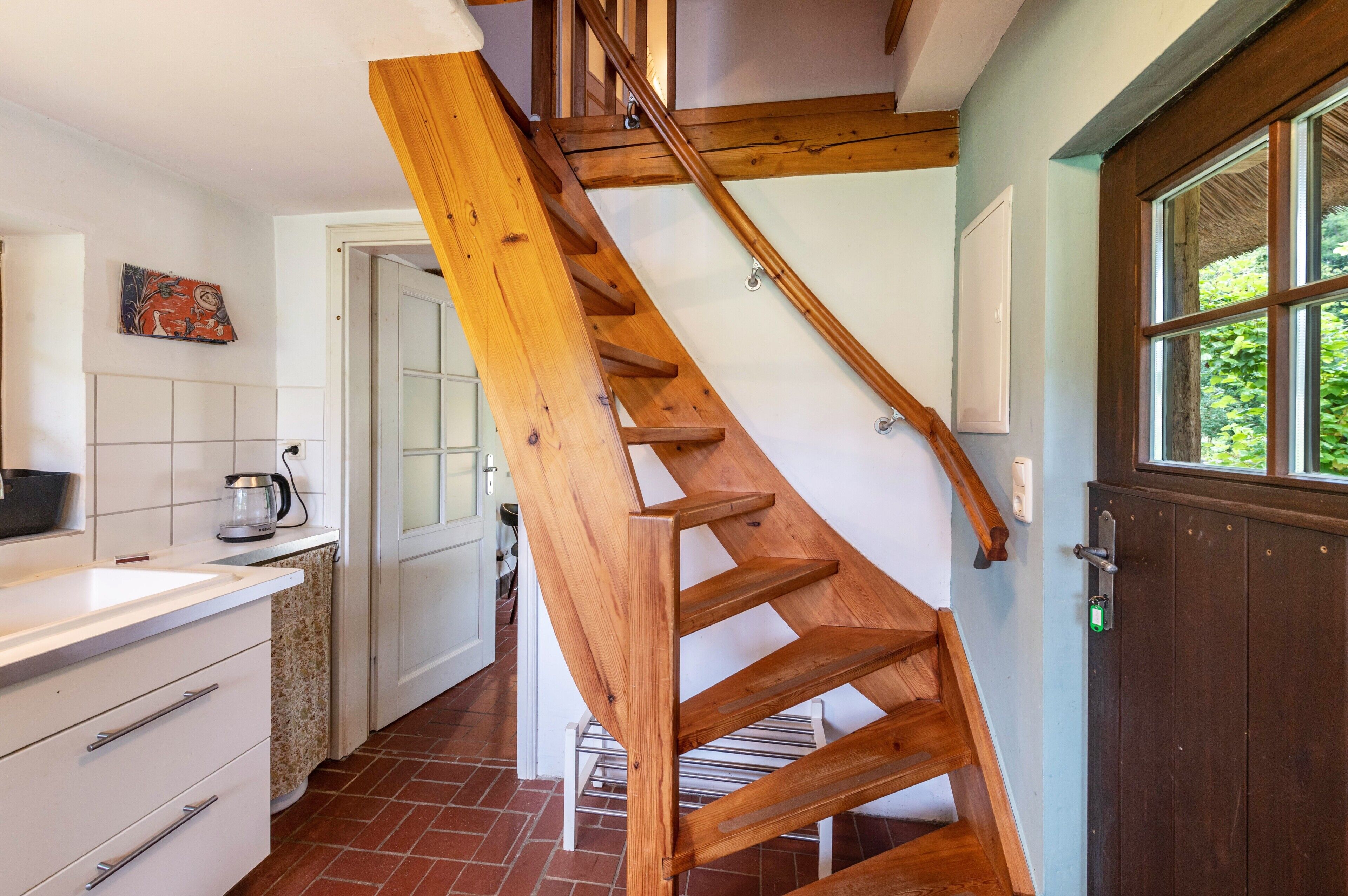 Eine Holztreppe in einer Küche mit weißen Schränken und einer gefliesten Spritzschutzwand.