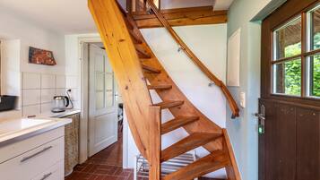 Eine Holztreppe in einer Küche mit weißen Schränken und einer gefliesten Spritzschutzwand.