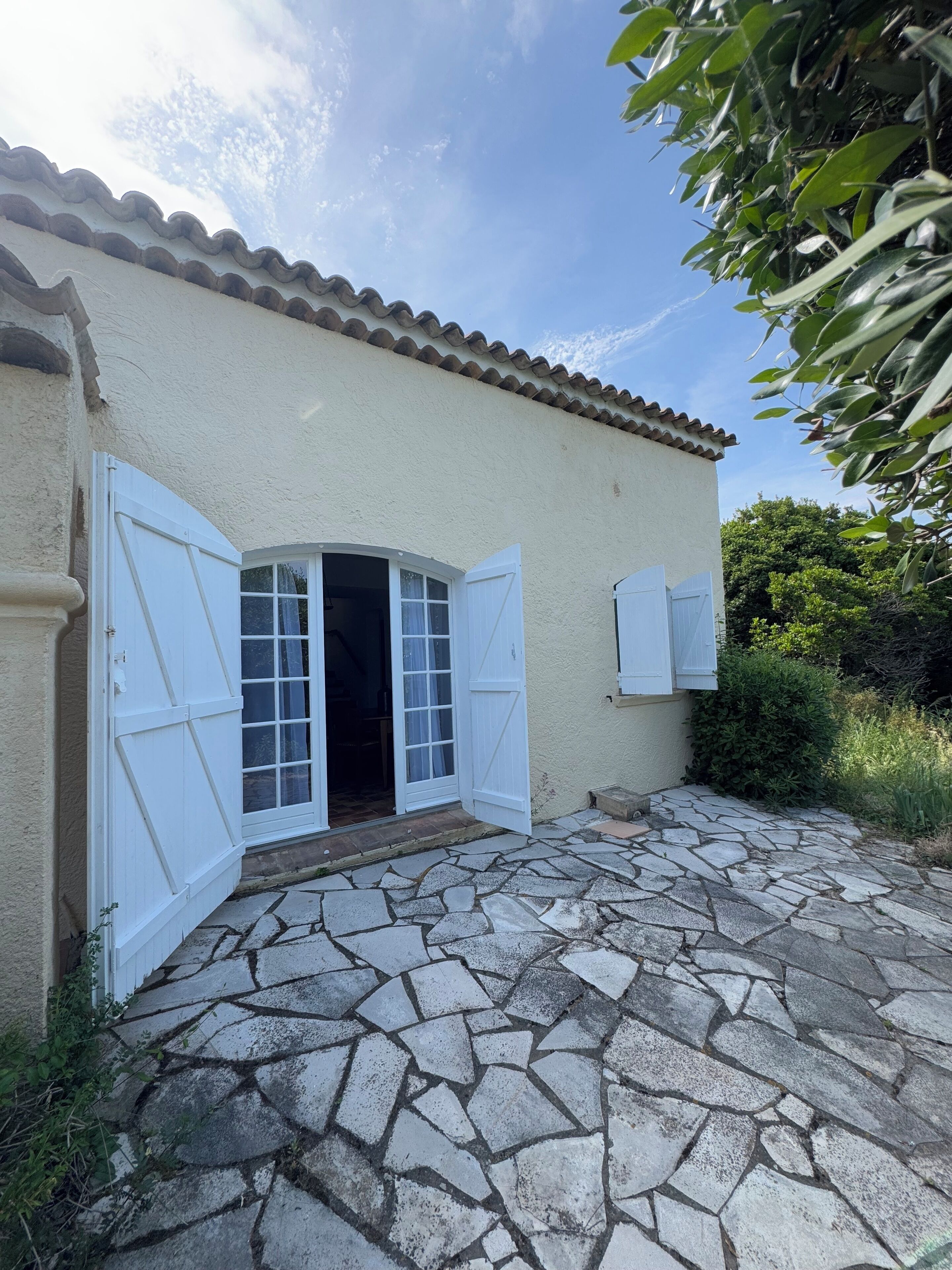 Una casa con ingresso in pietra, porte bianche e tetto in tegole.