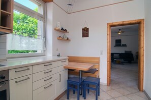 A kitchen with a window, wooden table, and blue chairs. - Apartment 'Renchglück' with Shared Terrace, Shared Garden and Wi-Fi (Renchen)