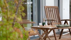 A wooden outdoor seating area with a table, two chairs, and a bottle of champagne.