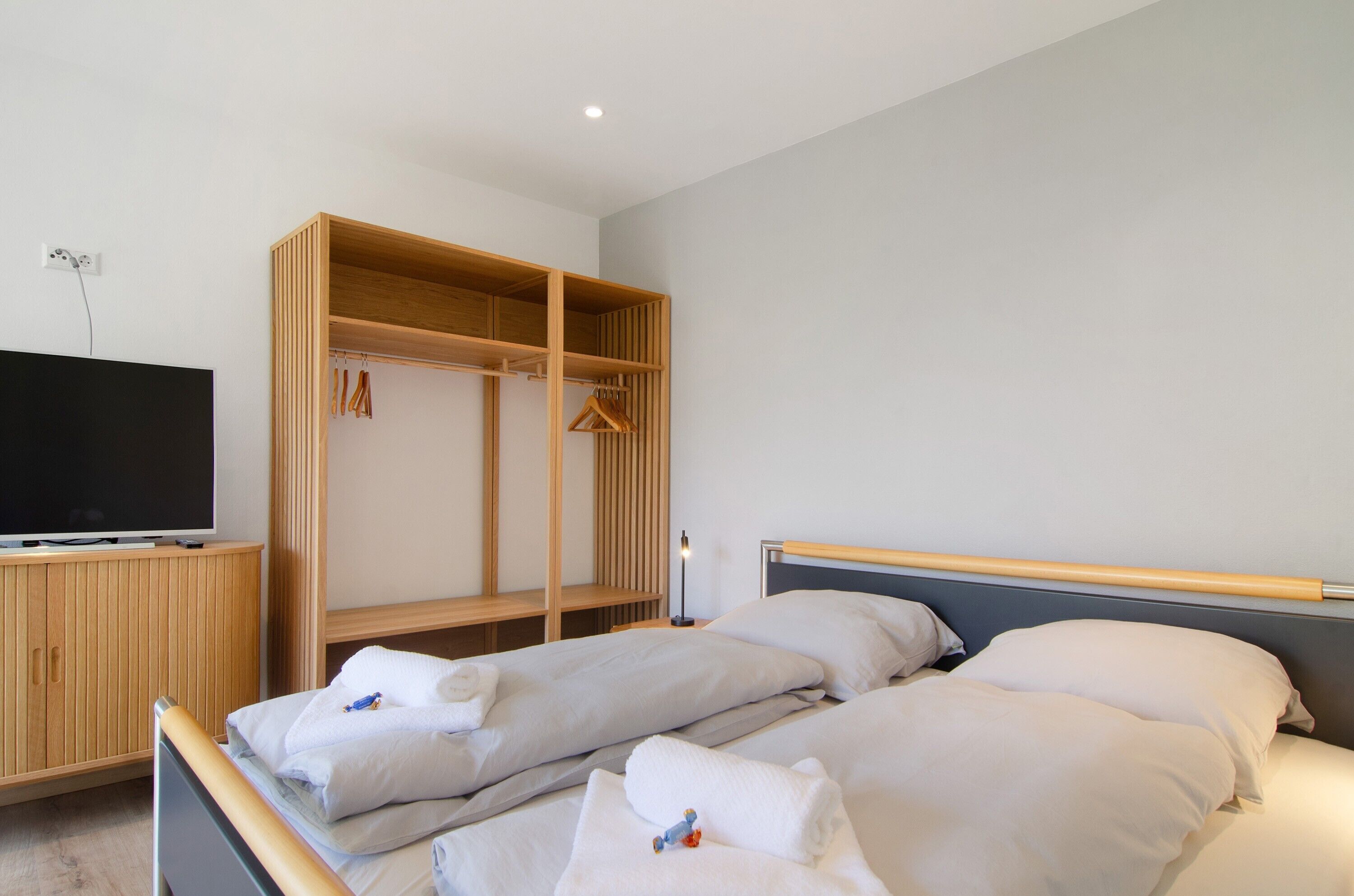 Ein Hotelzimmer mit zwei Betten, einem Fernseher, einem Holzschrank und einem Nachttisch.