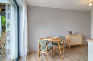 A dining area with a round table, four chairs, a cabinet, and a glass door leading outside.