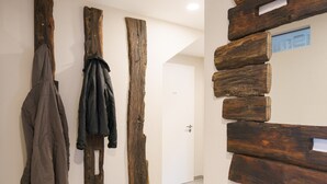 A hallway with wooden wall art and coats hanging on the left. - Apartment '2' with Private Terrace, Shared Garden and Wi-Fi (Gammertingen)