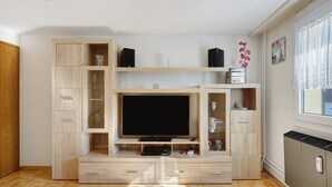 A modern living room with a built-in TV, wooden shelving, and a radiator. - Apartment 'Honacker' with Private Terrace, Shared Garden and Wi-Fi (Steißlingen)