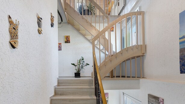 A staircase with wooden railings and a potted plant at the bottom. - Apartment 'Honacker' with Private Terrace, Shared Garden and Wi-Fi (Steißlingen)