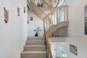 Una escalera con barandillas de madera y una planta en maceta al pie.