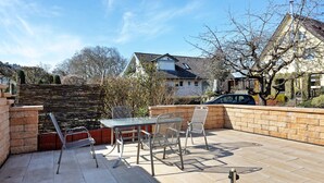 A patio with a table and chairs, a brick wall, and a view of a house. - Apartment 'Honacker' with Private Terrace, Shared Garden and Wi-Fi (Steißlingen)