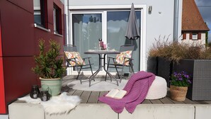 A patio with a table and chairs, a potted plant, a book, and a wicker basket with flowers. - Apartment '1' with Private Terrace, Shared Garden and Wi-Fi (Gammertingen)