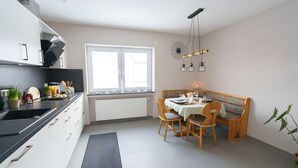 A modern kitchen with a dining area, featuring a built-in oven, a sink, and a window with blinds. - Apartment '1' with Private Terrace, Shared Garden and Wi-Fi (Gammertingen)