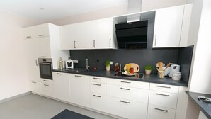 A modern kitchen with white cabinets, a black countertop, and a built-in oven. - Apartment '1' with Private Terrace, Shared Garden and Wi-Fi (Gammertingen)