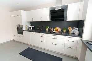 Una cocina moderna con gabinetes blancos, encimera negra y horno empotrado.