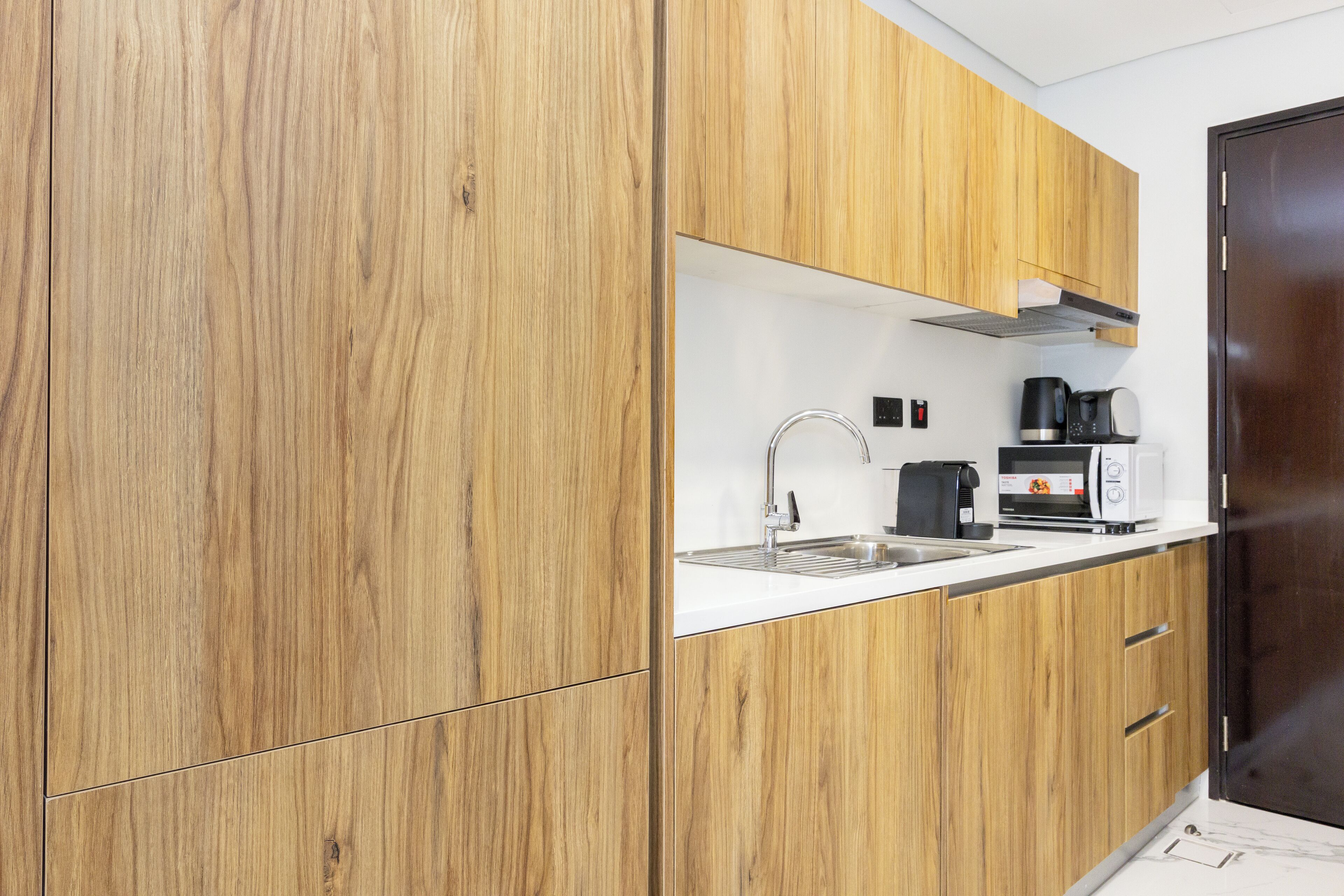 Eine moderne Küche mit Holzschränken, einer Edelstahl-Spüle, einer Kaffeemaschine und einem Toaster.