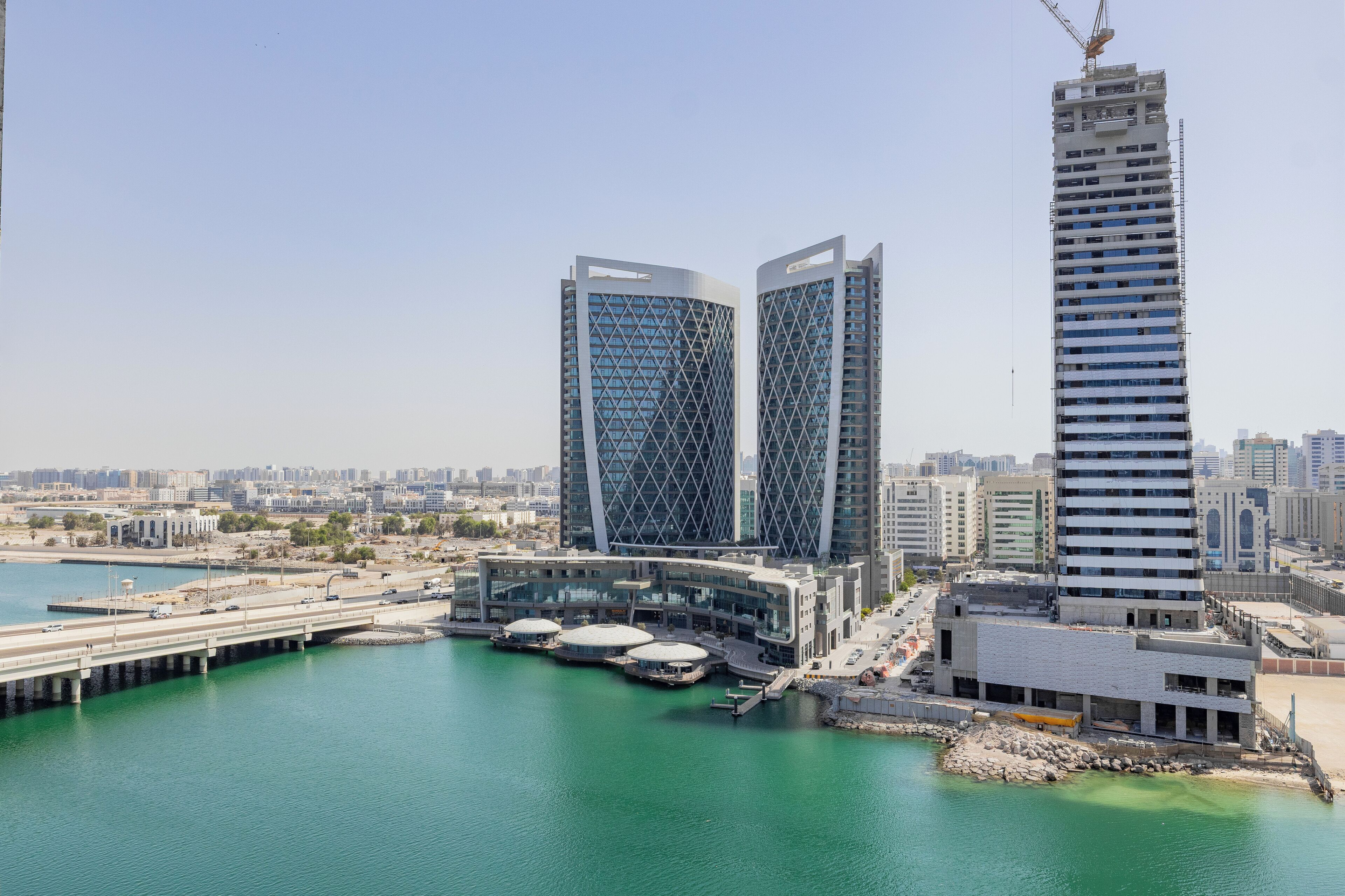 A modern building complex with a waterfront view, featuring two prominent towers and a high-rise structure.