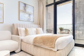 Un dormitorio moderno con una cama grande, un sofá y vistas de la ciudad a través de amplios ventanales.