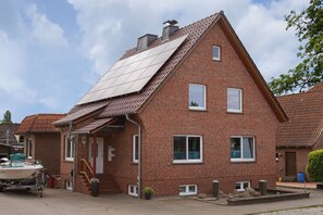 A red brick house with a sloped roof, solar panels, and a small front porch. - Apartment 'Apfelkorb' with Private Terrace and Wi-Fi (Jork)