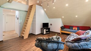 Une pièce de style loft avec un escalier en bois, un canapé, un lit et un téléviseur.
