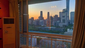 A room with a large window overlooking a cityscape at sunset.
