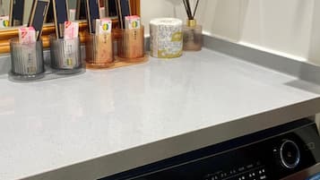 Un espace buanderie équipé d’un lave-linge Haier, d’un miroir et de divers produits de toilette disposés sur le comptoir.