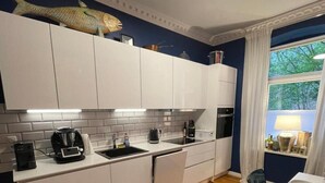 A modern kitchen with white cabinets, a black countertop, and a wooden floor. - Apartment '1' with Shared Terrace, Shared Garden and Wi-Fi (Kiel)