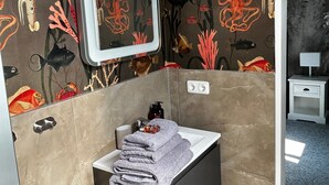 Un baño con lavamanos, espejo y una pila de toallas.