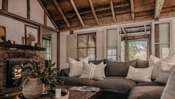 Una sala de estar acogedora con chimenea de piedra, techo de madera y un ventanal grande.